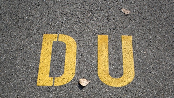 Zu sehen ist das Wort "DU" auf Asphalt geschrieben. © DoMonRai / photocase.de Foto: DoMonRai