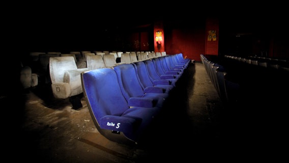 Ein schwach beleuchteter alter Kinosaal mit alten Kinosesseln. © kallejipp / photocase.de Foto: kallejipp