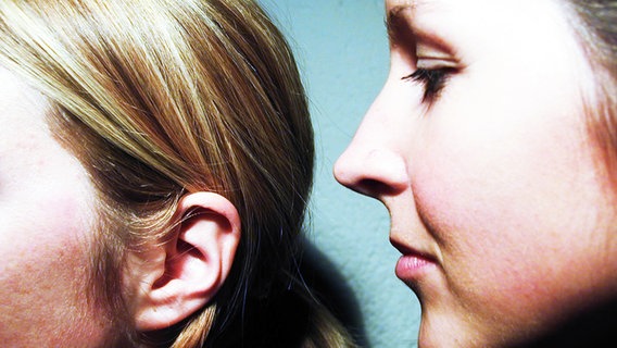 Ein Mädchen flüstert einem anderen etwas ins Ohr. © photocase.de Foto: wagg66