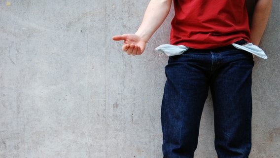 Ein Mann trägt eine Hose mit umgekehrten Taschen und hält die Hand auf. © photocase / AllzweckJack Foto: AllzweckJack