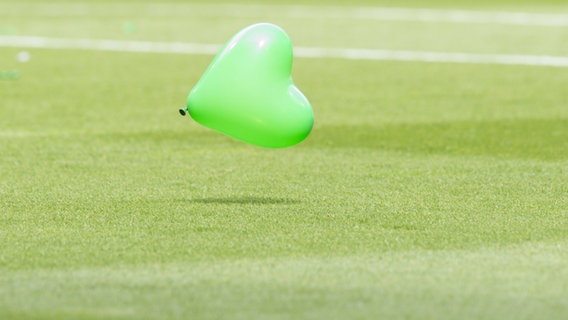 Ein grüner Luftballon fliegt über ein Fußballfeld. © picture alliane / dpa Foto: Jörg Sarbach