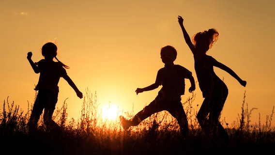 Drei Kinder spielen fröhlich im Sonnenuntergang. © altanaka / photocase.de Foto: altanaka / photocase.de