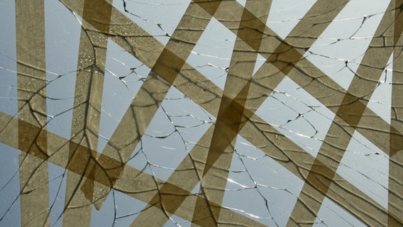 Eine kaputte Glasscheibe mit Rissen, die mit Klebeband abgeklebt sind. © Dot.ti / photocase.de Foto: Dot.ti / photocase.de