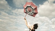 Eine Frau hält einen Regenschirm fest, der wegzufliegen droht. © Jonathan Schöps / photocase.de Foto: Jonathan Schöps / photocase.de