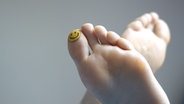 Zwei Füße mit einem Smiley auf dem großen Zeh des linken Fußes. © Seleneos / photocase.de Foto: Seleneos