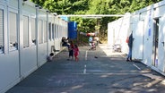 Zwischen zwei Containerreihen spielen Kinder. © n-joy Fotograf: Antje Barthold