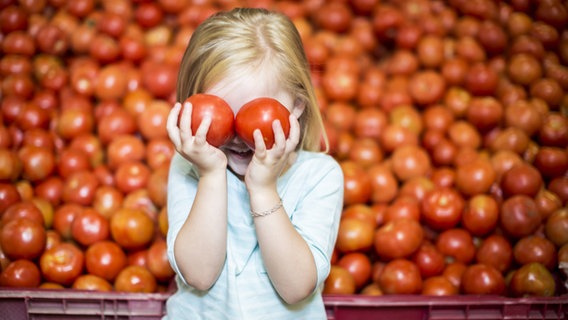 Ein Mädchen hält sich zwei Tomaten vor die Augen © imago/Westend61 