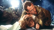 Der amerikanische Schauspieler Bruce Willis als New Yorker Cop John McClane und Bonnie Bedelia als seine Ehefrau Holly in einer Szene des Action-Thrillers "Stirb Langsam" ("Die Hard") von 1988. © picture-alliance / dpa 