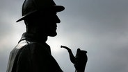 Zu sehen ist ein Detektiv im Profil mit Pfeife und Hut. © picture alliance / empics Foto:  Philip Toscano