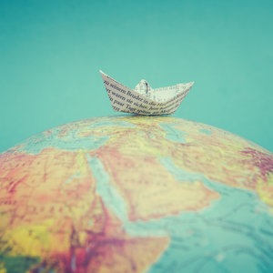 Ein Papierschiffchen liegt auf einem Globus. © suze / photocase.de Foto: suze