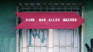Zu sehen ist ein Fenster, vor dem ein pinkes Schild hängt. Darauf steht: "Kann man alles machen." © ginger. / photocase.de Foto: ginger.