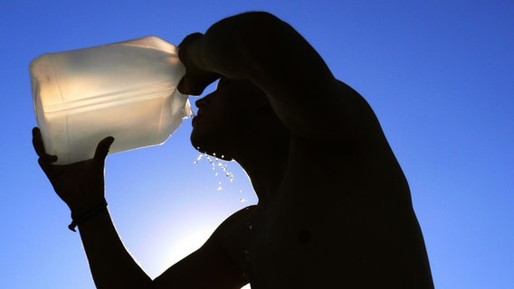 Ein Mann trinkt Wasser aus ienem großen Kanister. © photocase.de / skaisbon Foto: photocase.de / skaisbon