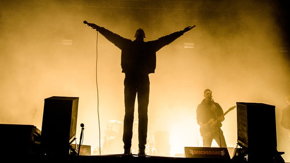 Der Schatten von einem Sänger auf der Bühne, der beide Hände in die Luft hebt. © NDR Foto: Benjamin Hüllenkremer