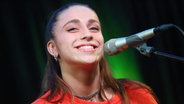 Die Sängerin Tate McRae lächelnd vor einem Mikrofon. © picture alliance/Capital Pictures Foto: Star Shooter/MPI