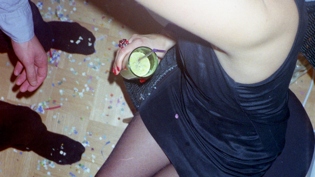 Partyszene: Eine Frau hält einen Drink in der Hand und tanzt. 