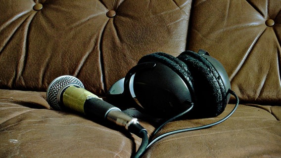 Ein Mikrofon und Kopfhörer liegen auf einem braunen Ledersofa. © Photocase Foto: Alwayshappy