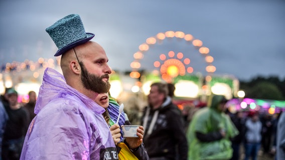 Mann mit Zylinder und Regencape beim Hurricane Festival in Scheeßel 2018. © NDR Foto: Benjamin Hüllenkremer