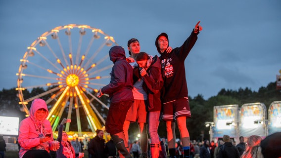 Menschen tanzen vor dem beleuchteten Riesenrad beim Hurricane Festival in Scheeßel 2018. © NDR Foto: Benjamin Hüllenkremer