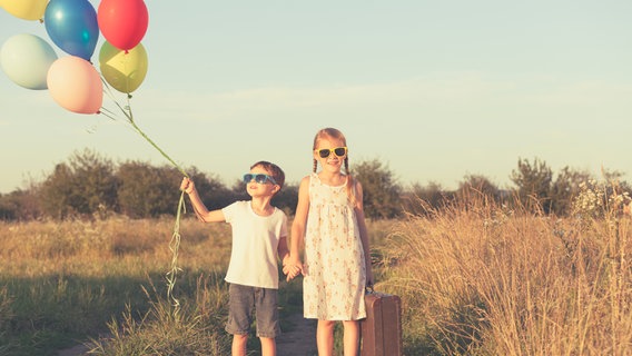 Zwei junge Kinder halten einige Luftballons. © photocase Foto: altanaka