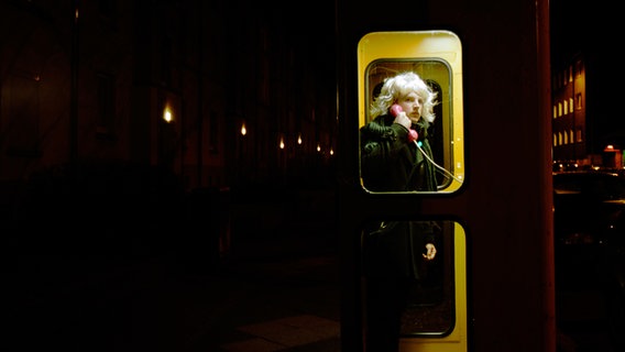 Ein junger Mann telefoniert in einer Telefonzelle bei Nacht. © photocase.de Foto: MI-Flo
