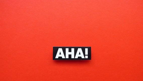 Zu sehen ist der Schriftzug "AHA!" in weißen Buchstaben auf rotem Grund.  