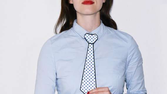 Eine Frau mit blauer Bluse hält sich eine Krawatte vor den Oberkörper. © FemmeCurieuse / photocase.de Foto: FemmeCurieuse / photocase.de