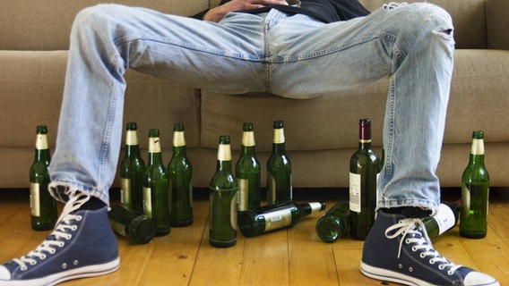 Zu sehen sind die Beine eines Mannes und viele Bierflaschen, die auf dem Boden stehen. © imago/Westend61 Foto: Westend61