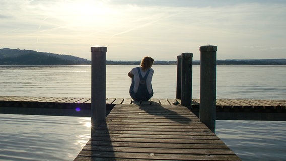 Eine Frau sitzt einsam auf einem Steg. © bunnyface / photocase.de Foto: bunnyface / photocase.de
