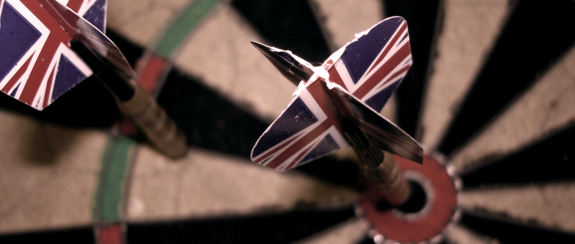 Zwei Dartpfeile mit der englischen Flagge als Flight stecken in einem Dartboard., © madochab / photocase.deFoto: madochab / photocase.de