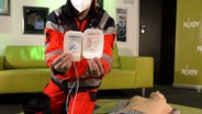 Das Bild zeigt einen Notfallsanitäter mit einem Defibrillator (AED). © N-JOY Foto: N-JOY