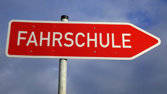 Auf einem roten Wegweiser-Schild steht "Fahrschule". © Imago/Steinach 