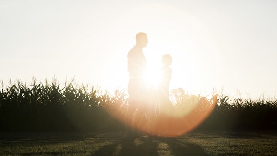 Eine Familie spaziert im Sonnenlicht durch die Natur. © picture alliance / PhotoAlto Foto: Ale Ventura
