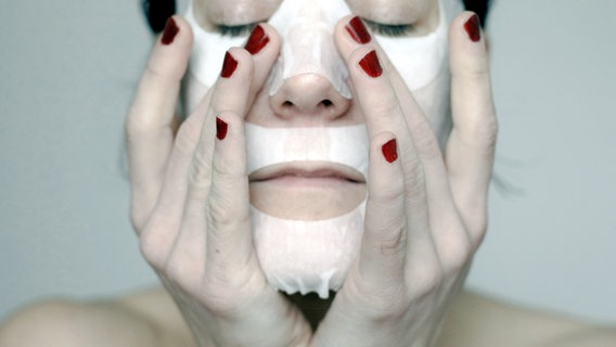 Eine Frau fährt mit den Fingern über ihre Gesichtsmaske. © inkje / photocase.de 