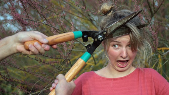 Einer Frau wird mit einer Heckenschere das Haar geschnitten. © Julia Straub / photocase.de Foto: Julia Straub / photocase.de