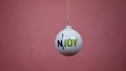 Von Stars signierte N-JOY Weihnachtskugeln vor einem rosa Hintergrund. © NDR/N-JOY Foto: NDR/N-JOY