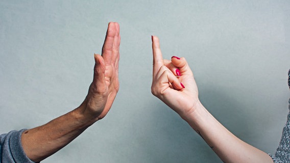 Eine weibliche Hand zeigt den Mittelfinger, eine männliche Hand macht eine abwehrende Geste. © esmaqe / photocase.de Foto: esmaqe / photocase.de