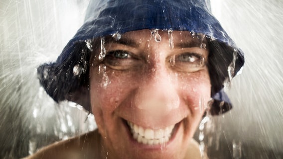 Eine Frau steht mit einem Hut unter der Dusche. © inkje / photocase.de 