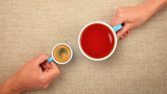 Zwei Hände halten eine kleine Tasse Espresso und eine große Tasse Tee. © BreakingTheWalls / photocase.de Foto: BreakingTheWalls