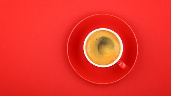 Eine rote mit Kaffee gefüllte Tasse auf rotem Untergrund. © photocase.de / BreakingTheWalls Foto: photocase.de / BreakingTheWalls