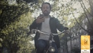 Ein Mann tippt auf dem Smartphone, während er Fahrrad fährt. © NDR/N-JOY 