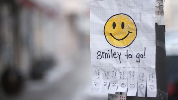 An einer Laterne hängt ein Zettel mit einem Smiley und den Worten "Smiley to go". © Ane_W / photocase.de Foto: Ane_W / photocase.de