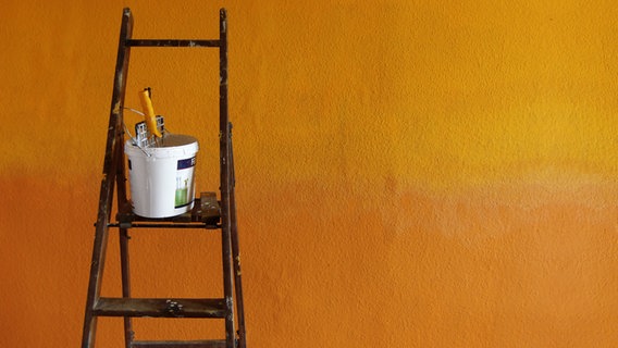 Eine Leiter steht vor einer orangefarbenen Wand. © jCOP / photocase.de Foto: jCOP / photocase.de