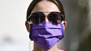 Eine junge Frau trägt eine Gesichtsmaske und eine Sonnenbrille. © picture alliance/dpa Themendienst Foto: Kirsten Neumann