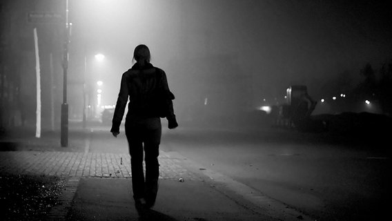 Eine Frau geht in einer nebligen Nacht an Straßenlaternen vorbei. © Sightkick / photocase.de Foto: Sightkick / photocase.de