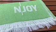 Das nachhaltige N-JOY Tuch in Grün mit Logo. © NDR/N-JOY 