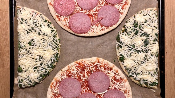 Zwei Pizzen liegen jeweils in der Mitte zerteilt auf einem Backblech. © NDR/N-JOY Foto: Dennis Bangert