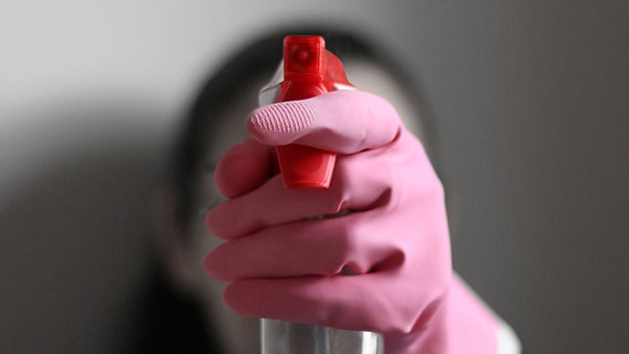 Eine Frau mit Gummihandschuh hält eine Flasche mit Putzmittel in die Kamera. © bruzzomont / photocase.de Foto: bruzzomont / photocase.de