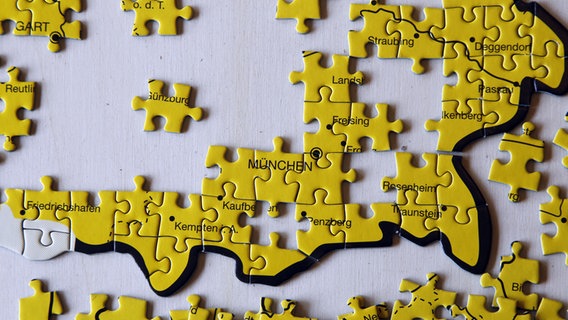 Puzzleteile mit Städtenamen, die teilweise schon zu einer Landkarte zusammengesetzt sind. © picture alliance Foto: R4200