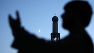 Mann vor Moschee mit Mondsichel im Hintergrund. © EPA 