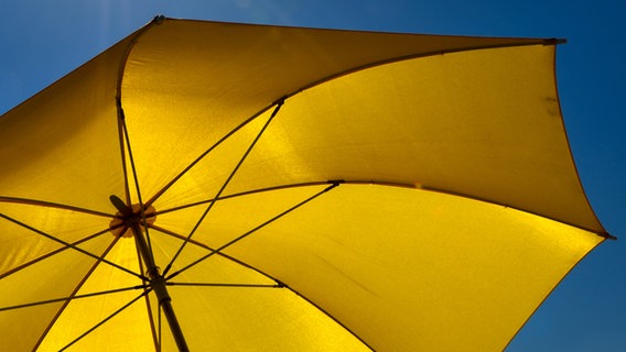 Die Sonne scheint auf einen gelben Regenschirm. © photocase.de / grafxart Foto: photocase.de / grafxart
